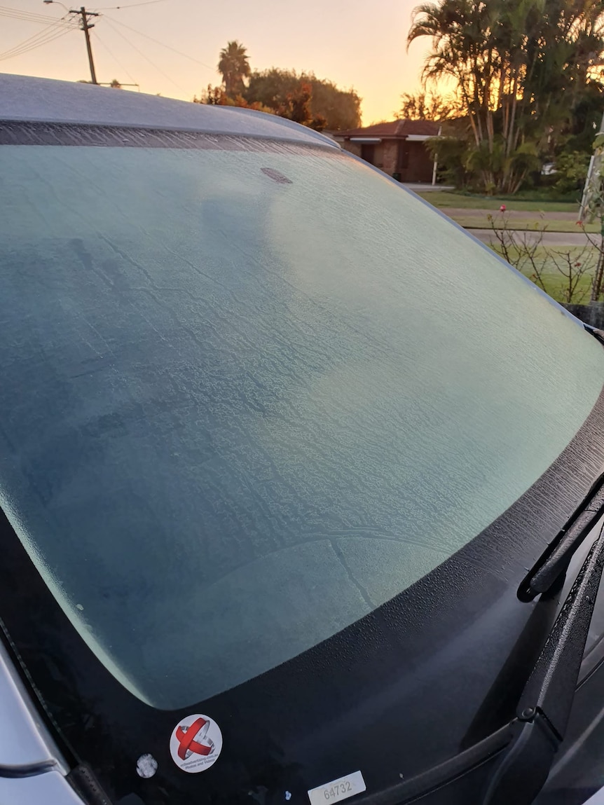 A frozen car rear windscreen with a rising sun in the background.