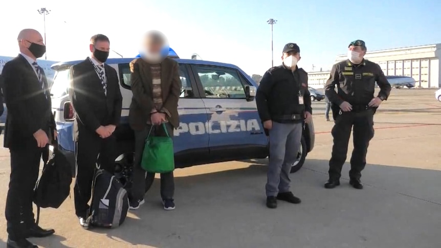 A man with a blurred out face is surrounded by Italian police