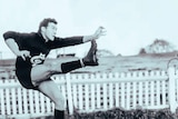 A man in a Carlton jersey in a kicking pose in a field.