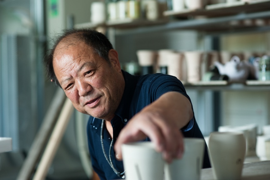 A man reaches for a piece of pottery