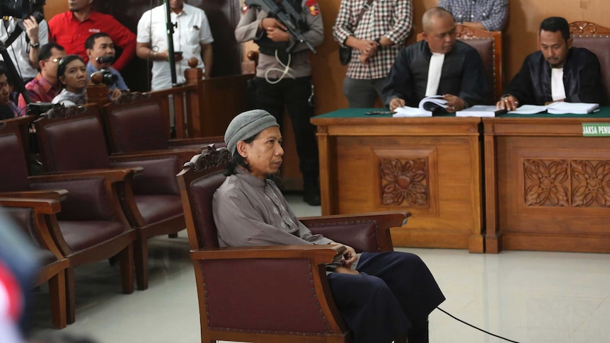 Radical Islamic cleric Aman Abdurrahman in court. He is sitting in the middle of the court room.