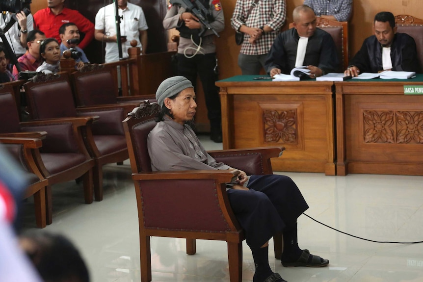 Radical Islamic cleric Aman Abdurrahman in court. He is sitting in the middle of the court room.