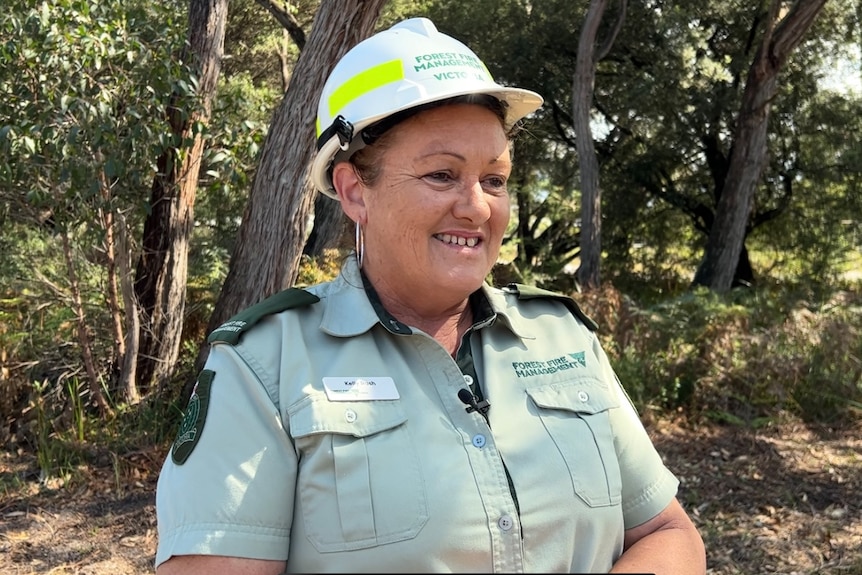 A woman wearing  hardhat stands in a forest
