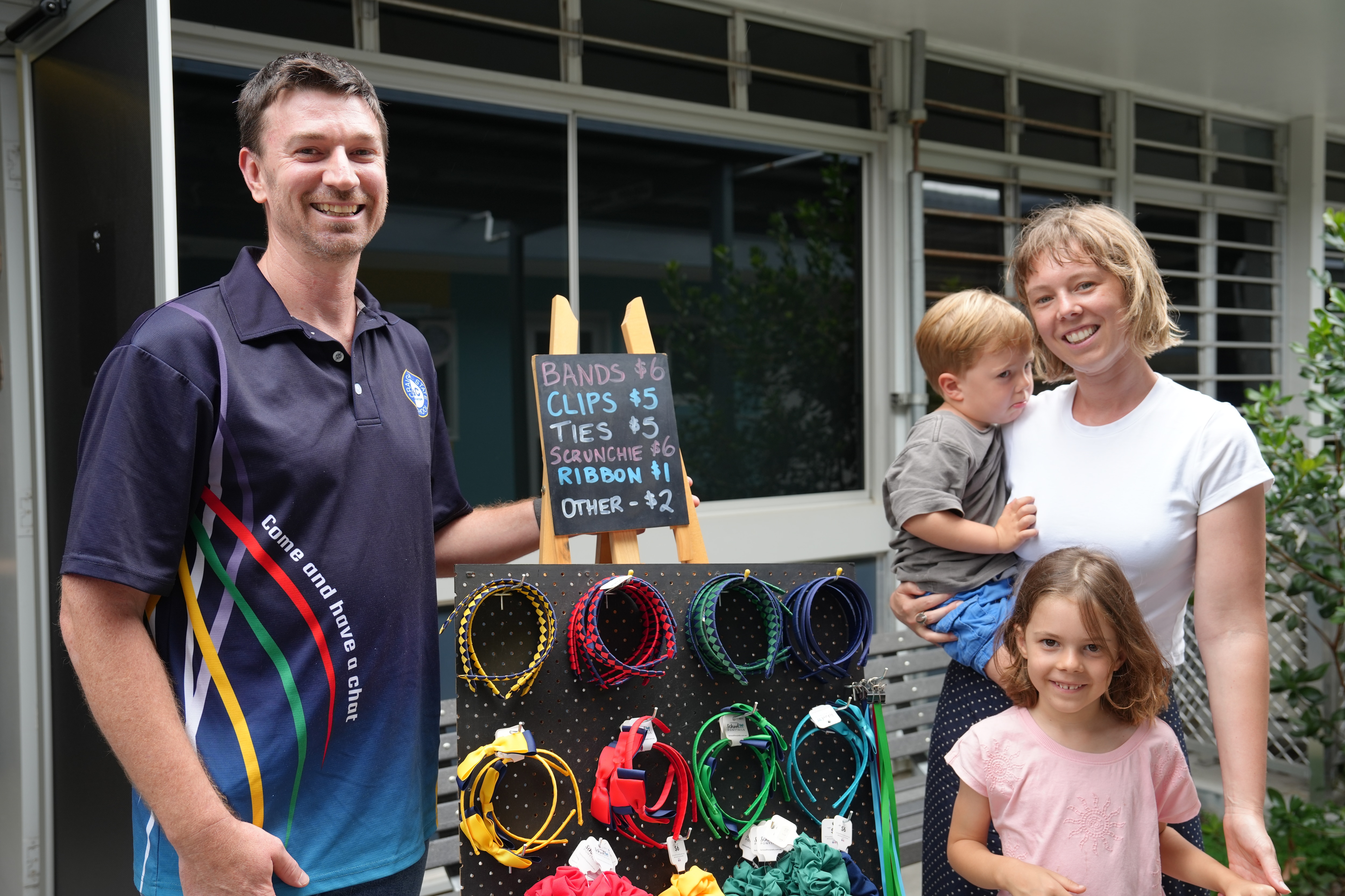 Um homem, uma mulher e duas crianças vendendo material escolar. 