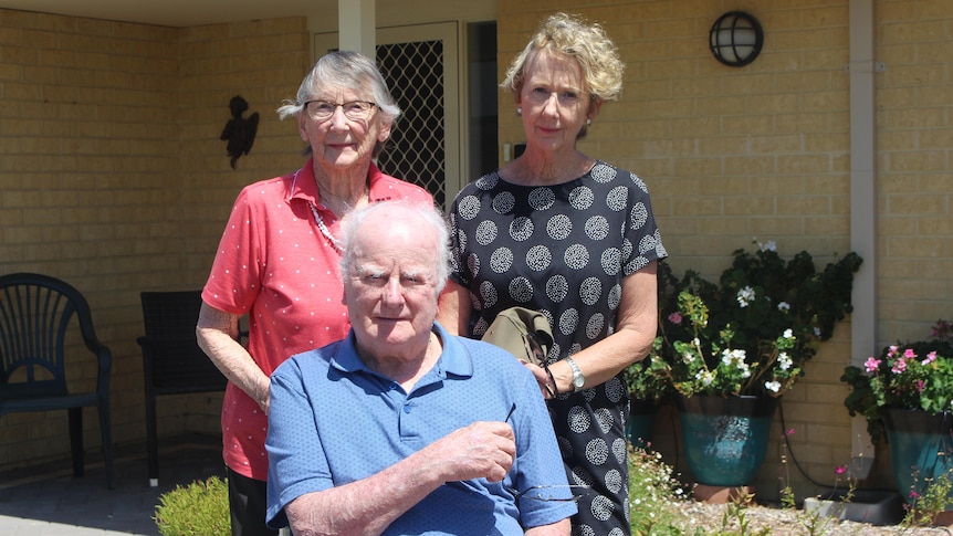 The couple and daughter Elaine are out the front of a house, Norman is using a wheelchair