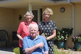 The couple and daughter Elaine are out the front of a house, Norman is using a wheelchair