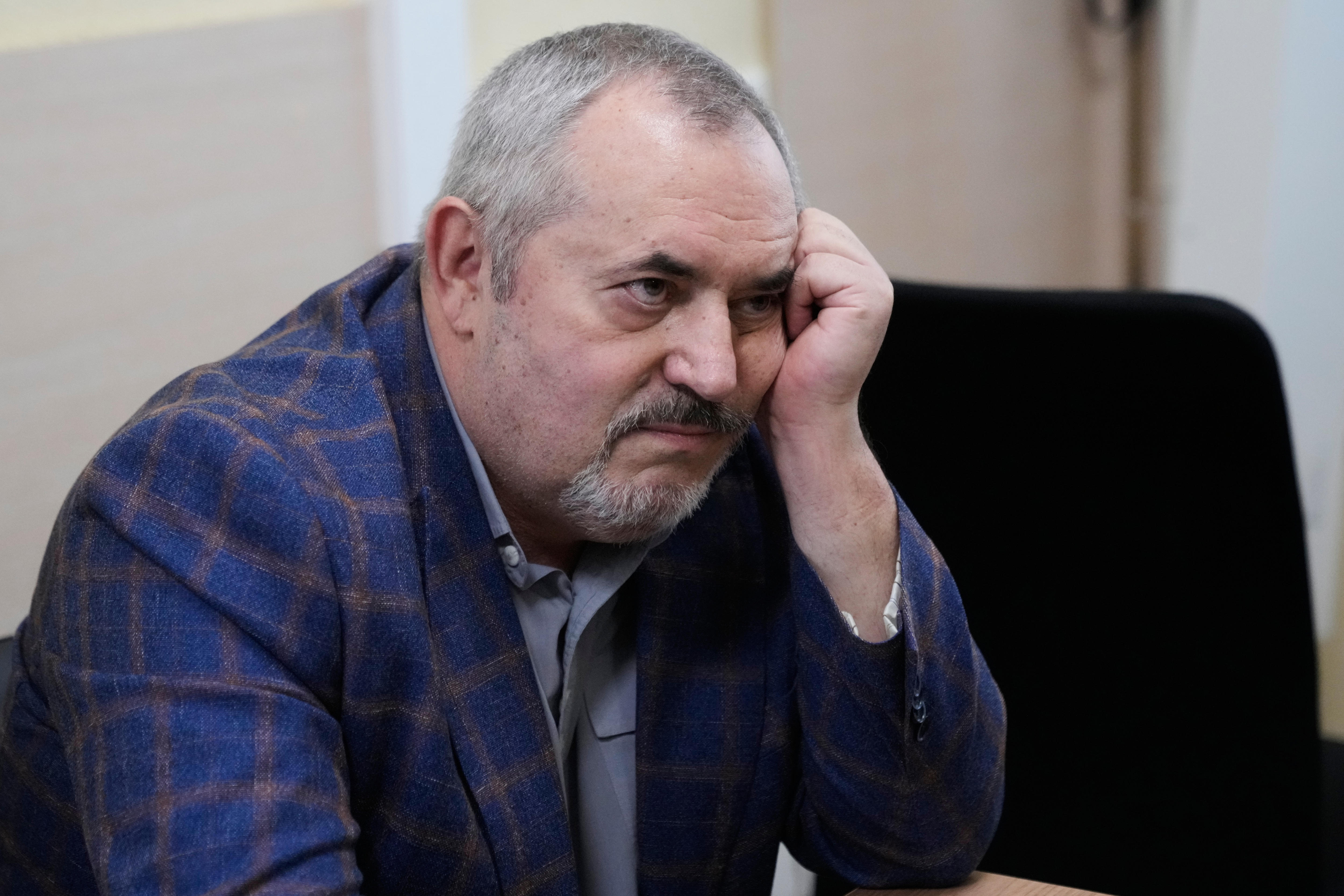 A man sits holding his head in his hand. 