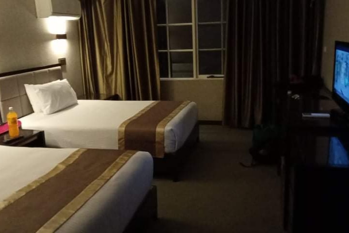 A hotel room showing two single beds and a television.