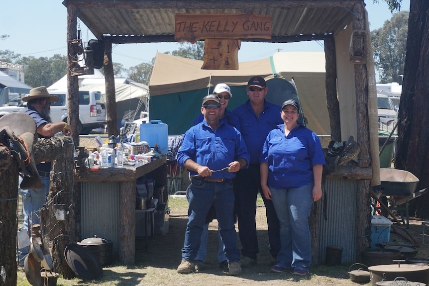 Four people stand together in an open shed