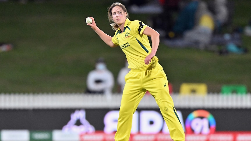 An Australian female professional cricketer holds a ball in her right hand.