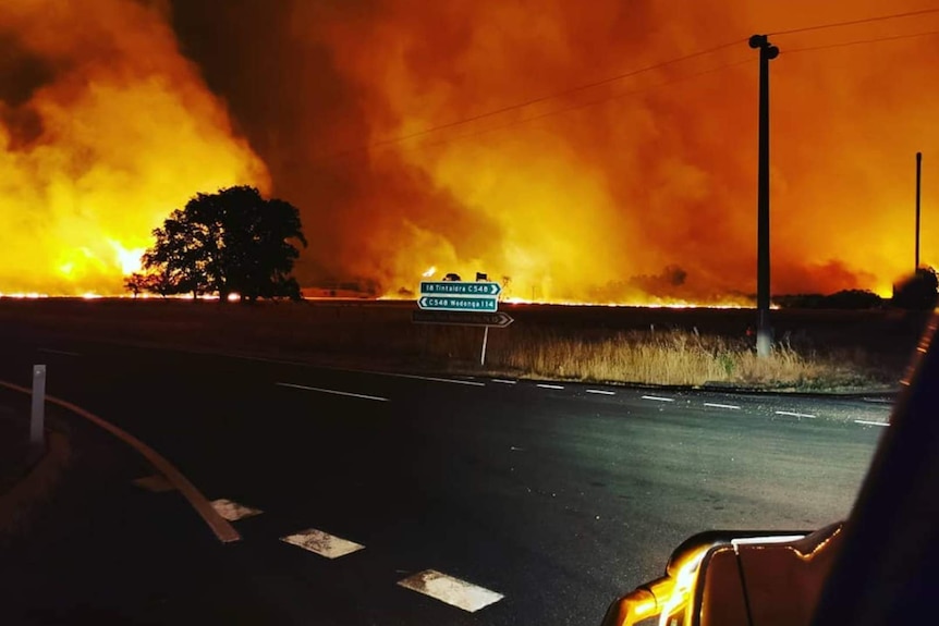 Fires burn in paddock behind street sign