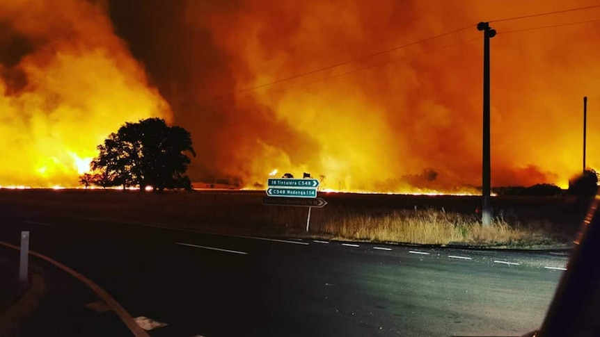 Fires burn in paddock behind street sign