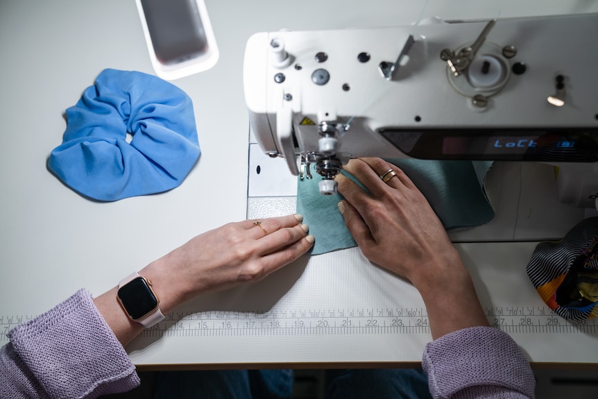 Only Barbara's hands are visible while she sits and works on her sewing machine