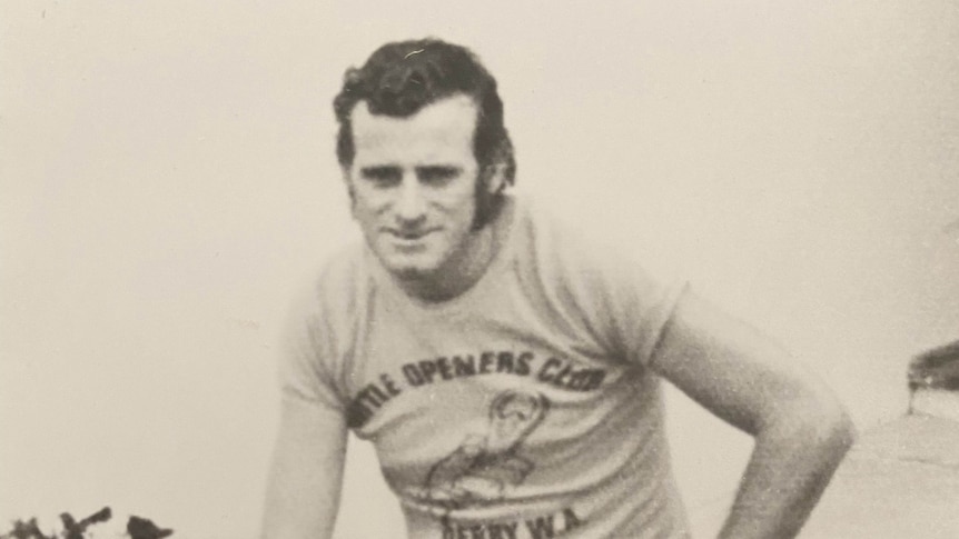 A sepia-toned photograph of Desmond, wearing a tshirt, sitting on a low brick fence.