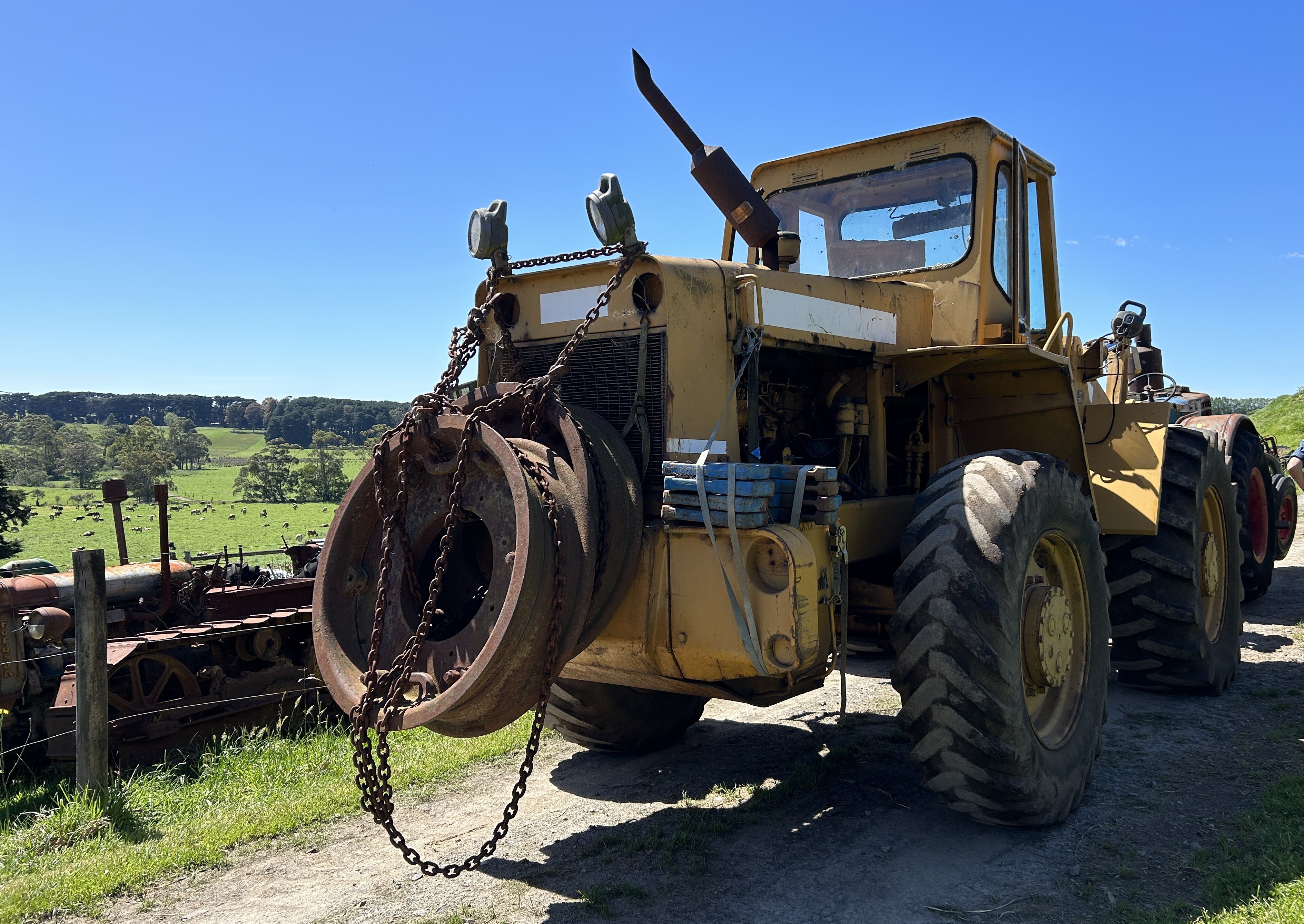 An old tractor on a gravel track next to a paddock.