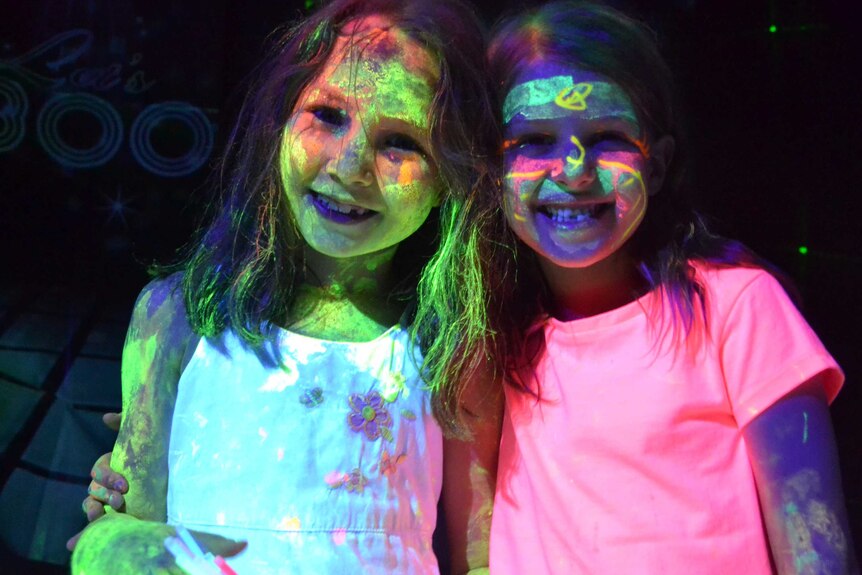 Two girls wear neon face-paint at Julian Scharf's party