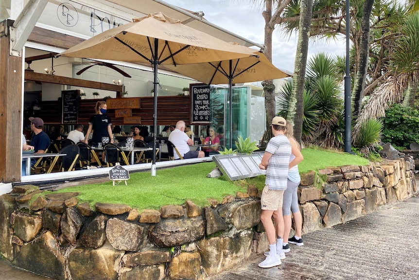 People at a cafe on a boardwalk by the beach.