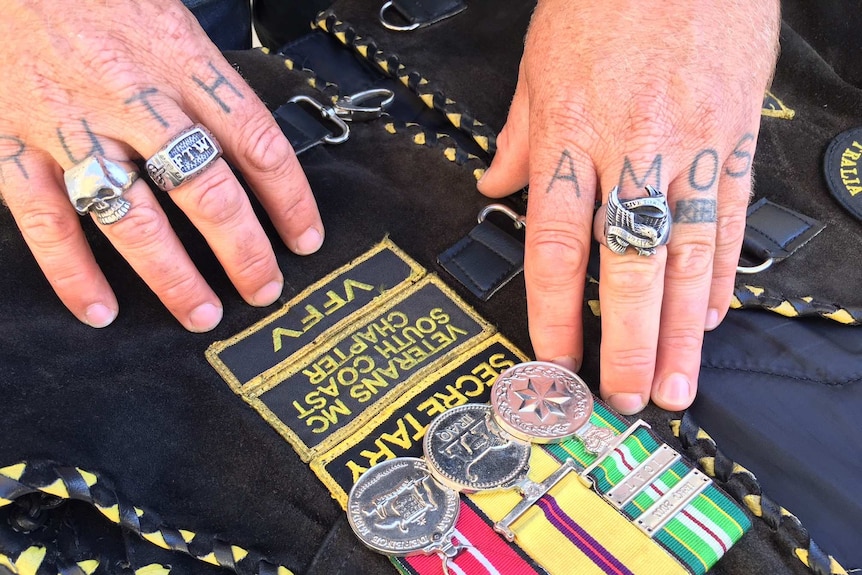 Derek Pyrah's tattooed fingers rest near his three service medals.