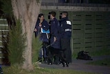 Victorian Police stand outside a house in Melbourne after 19 search warrants were executed