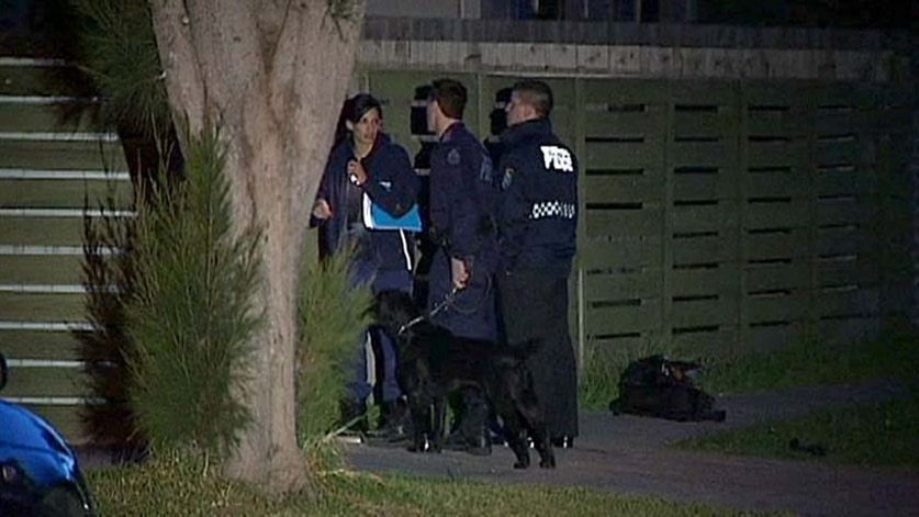 Victorian Police stand outside a house in Melbourne after 19 search warrants were executed