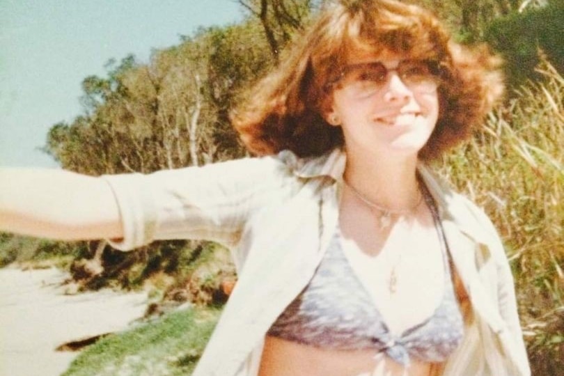 A woman smiling on a beach in the 1970s.