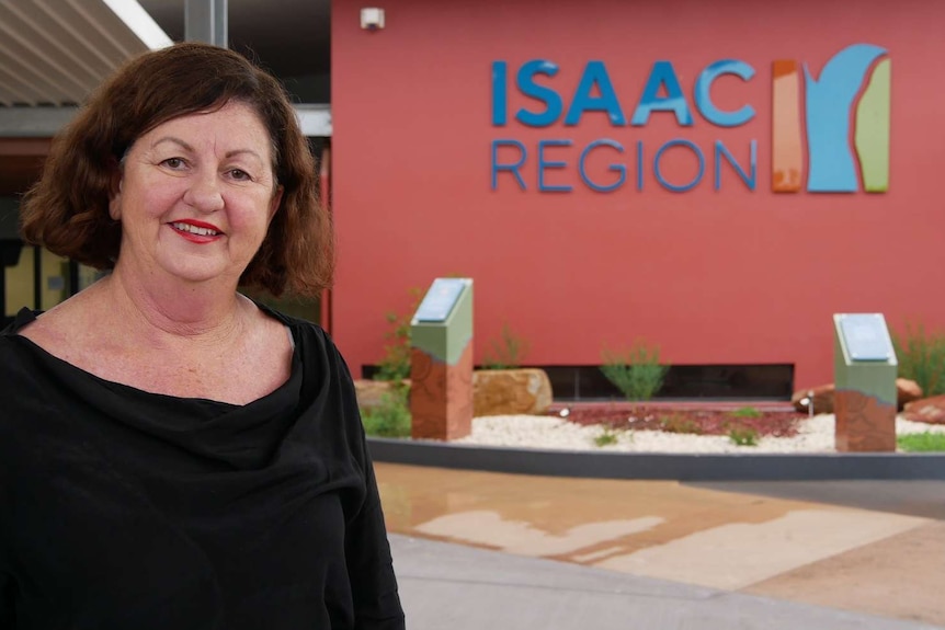 A woman stands in front of an Isaac Region sign and smiles at the camera.