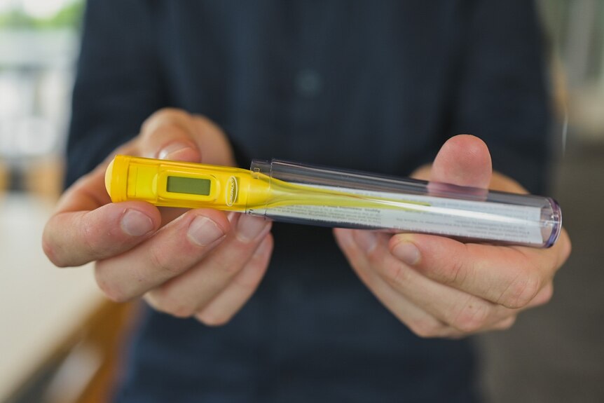 Close-up of hands holding a thermometer for fevers