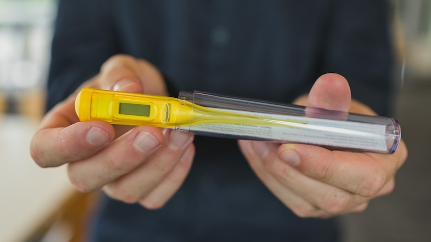 Close-up of hands holding a thermometer for fevers