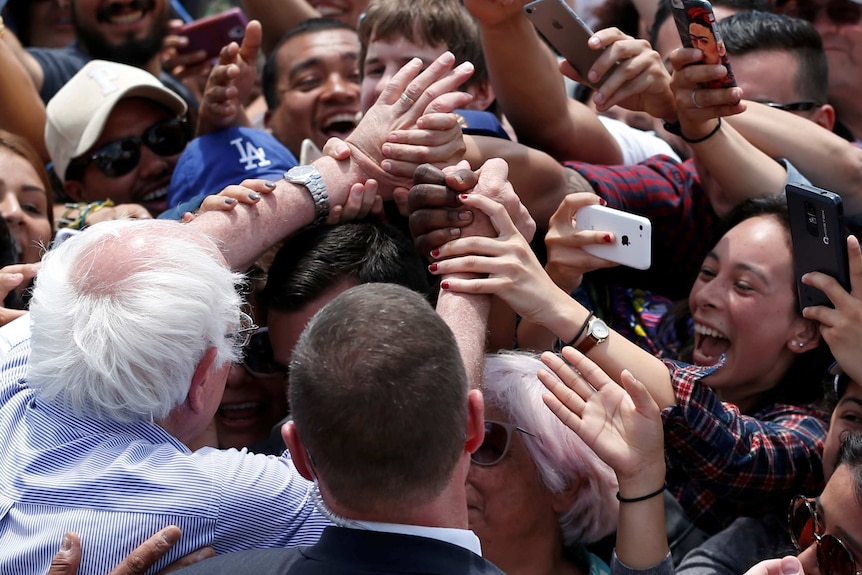 Bernie Sanders with supporters grabbing his hands