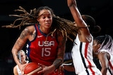 Brittney Griner holding a basketball with her braids flowing around her on the basketball court