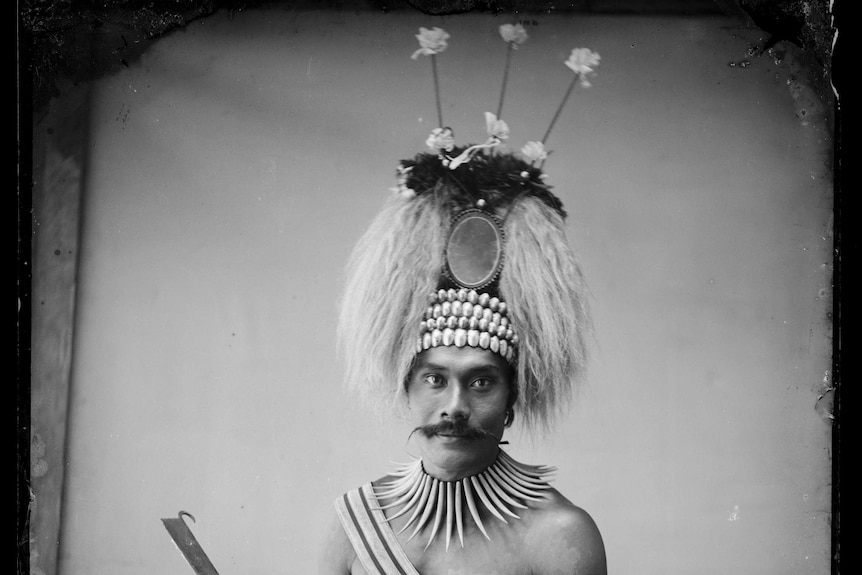 A black and white photo of a man wearing a headdress and wearing a traditional outfit.