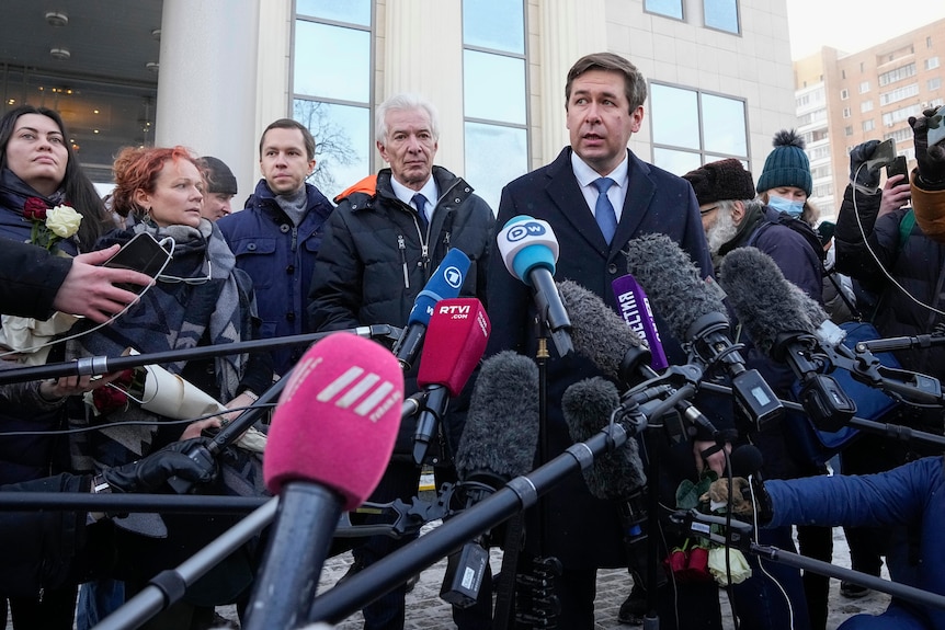 A man speaks to a gathering of journalists