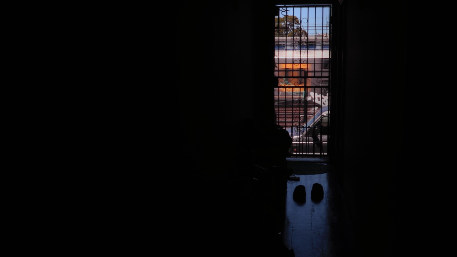 A dark image showing a sliver of an open doorway and a train passing.