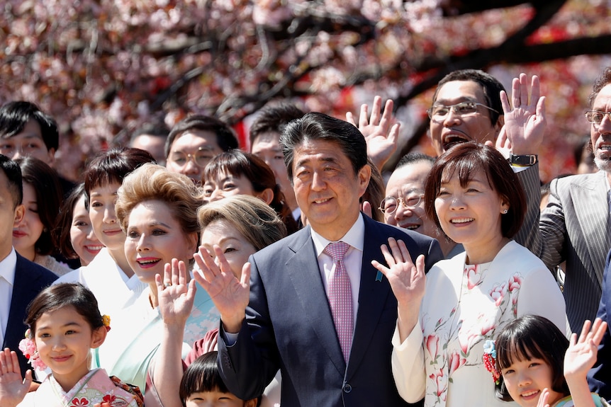 Shinzo Abe and his wife Akie pose with guests during a cherry blossom viewing party