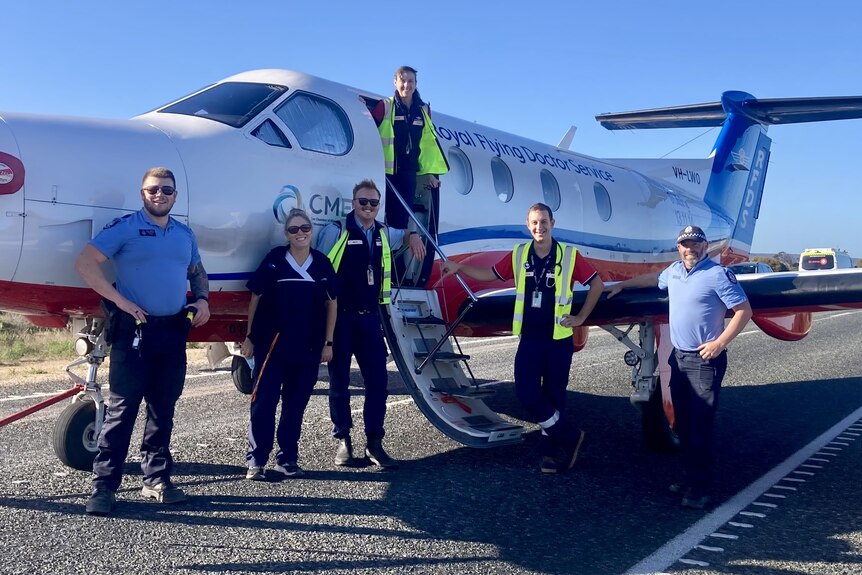 RFDS crew and police stand next to a plane. 