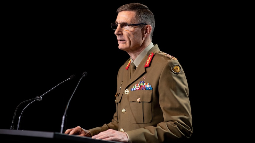 Angus Campbell in uniform speaks at a lectern against a black background