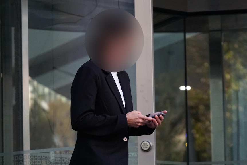 Image of a person outside court in Perth. Their face is blurred and they are wearing a black suit jacket with a white shirt.