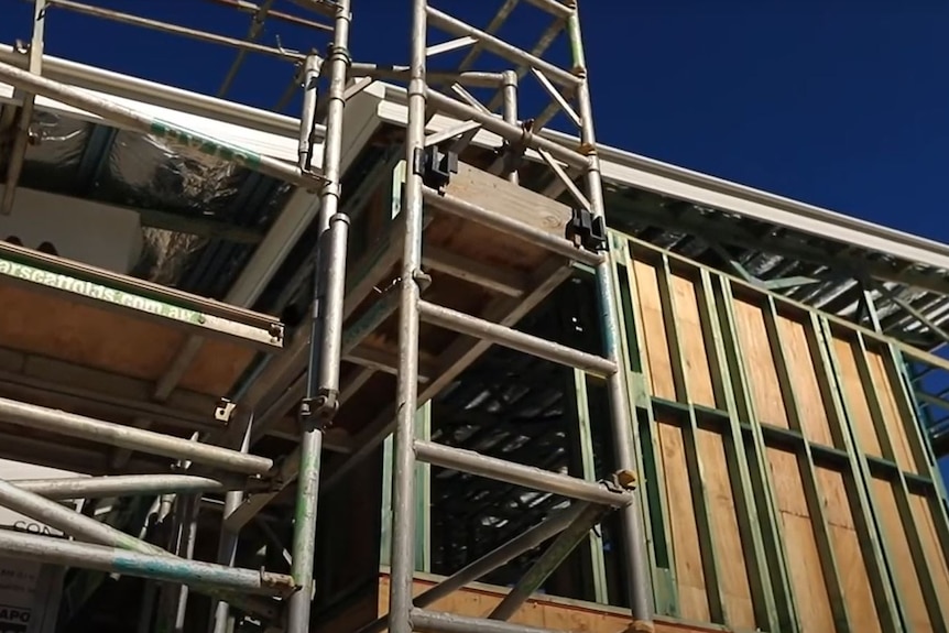 Building with frame, roof and scaffolding
