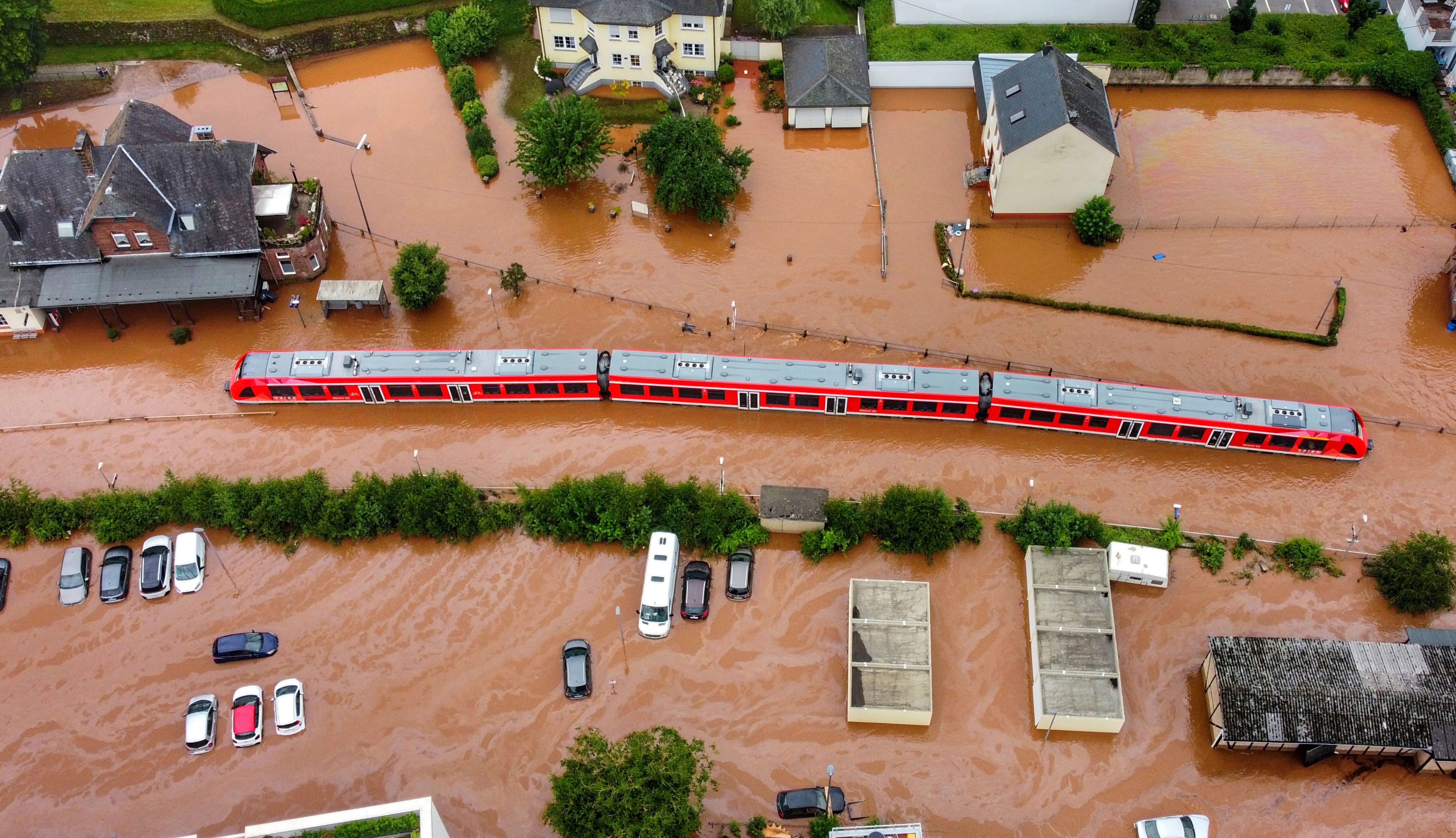 An aerial shot of a half submerged train in a flooded village.