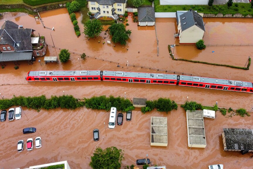An aerial shot of a half submerged train in a flooded village.
