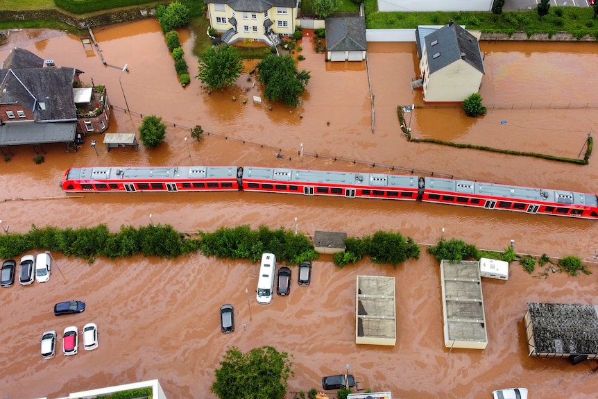 An aerial shot of a half submerged train in a flooded village.