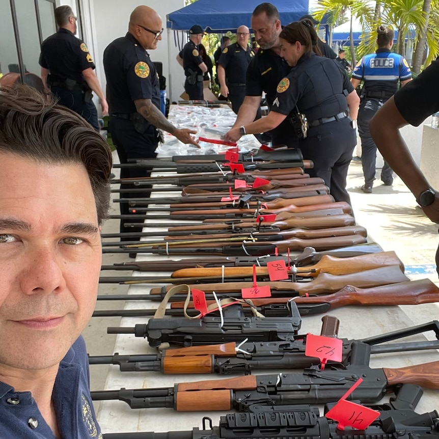 Miami City Commissioner Ken Russell stands in front of guns donated at the Guns 4 Ukraine event
