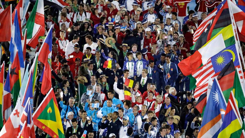 Athletes surrounded by flags march into the Olympics closing ceremony.