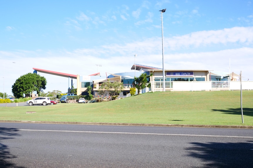 A building on a slight hill with a car park to the left and lawn bowls green to the right