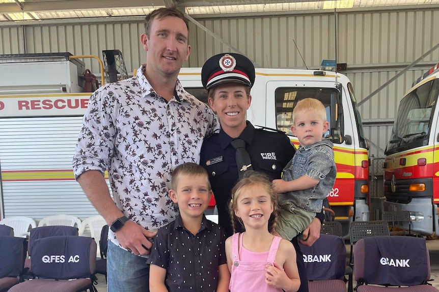 A man, woman and three children pose for a photo at a fire station.