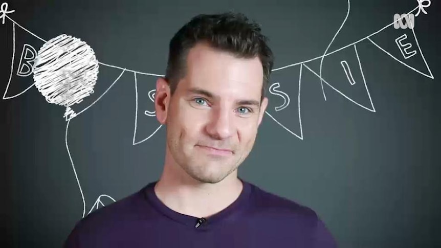 Man stands in front of blackboard showing drawing of bunting flags