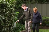 Christopher Pascoe hoses the garden while Yvonne Pascoe watches