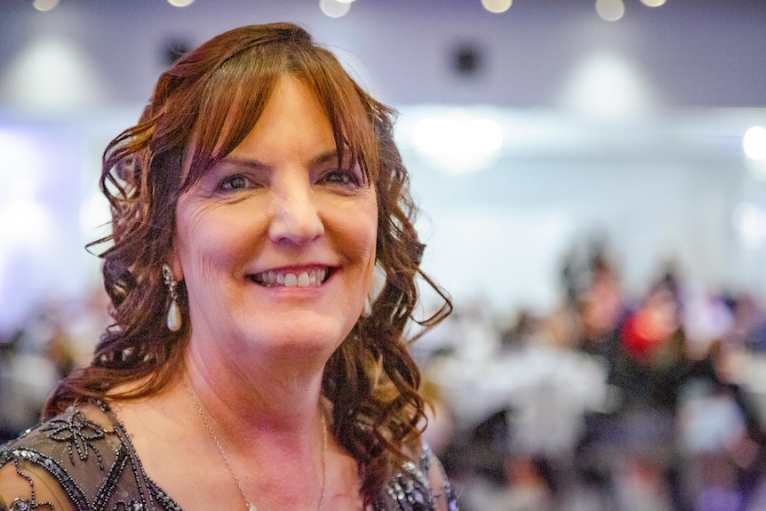 A portrait of a woman with curly brown hair, smiling at the camera.