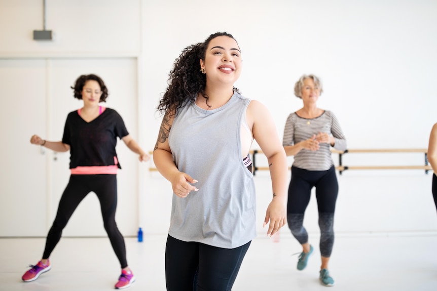 A woman is smiling while dancing in a dance studio.
