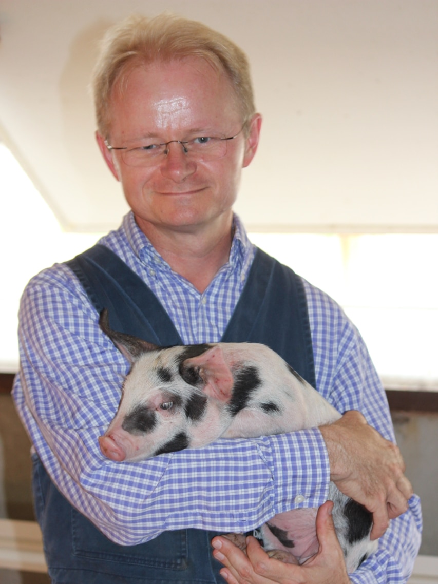 World Organisation for Animal Health president Mark Schipp holding a pig.